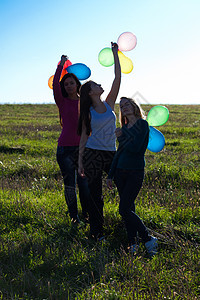 三名美丽的年轻女子 带着气球进入田野对抗自由友谊假期天空蓝色团体头发快乐女孩们女性图片