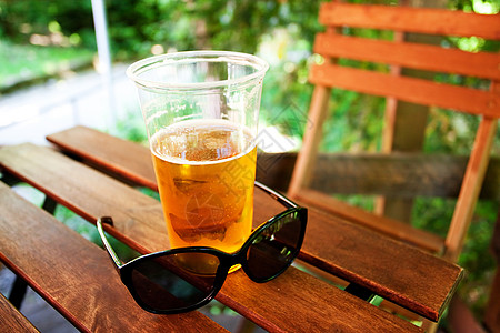 玻璃杯啤酒和太阳镜 站在木制桌子上图片