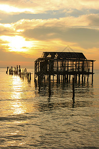 日出时的旧木制码头轮椅 康龙岛 坎布海洋橙子热带太阳天空钓鱼棕榈剪影天堂高跷图片