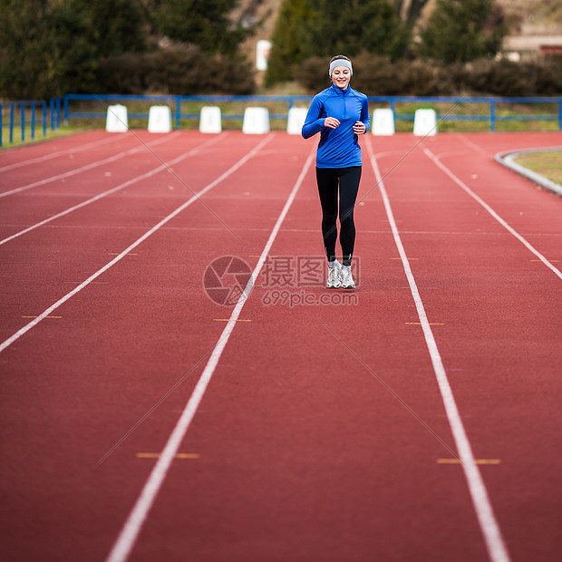 年轻妇女在赛场和田径体育场跑步肌肉赛跑者女孩慢跑者蓝色女性场地运动装活动火车图片