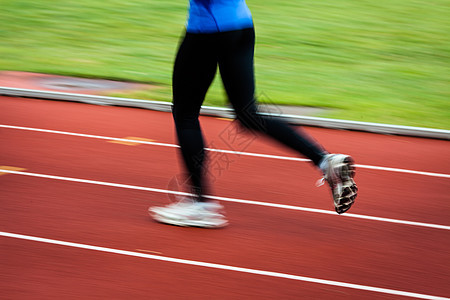 年轻妇女在赛场和田径体育场跑步(运动模糊)图片