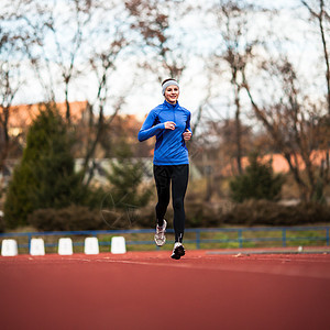 年轻妇女在赛场和田径体育场跑步女士运动装蓝色女性快乐肌肉竞赛竞技训练火车图片