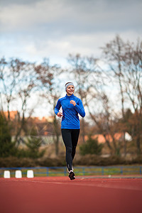 年轻妇女在赛场和田径体育场跑步火车女士蓝色竞技女孩娱乐运动员竞赛女性训练图片