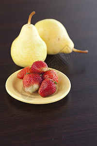 板上草莓和木制桌上的梨子叶子浆果食物水果营养水平桌子绿色盘子红色图片