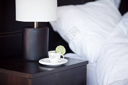 床铺和枕头 在床边桌子和灯台上喝茶气氛停留毛巾国王杯子窗户飞碟柠檬食物木头图片