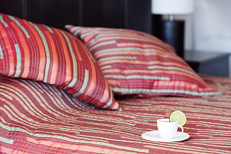 床铺上有两个枕头 毯子上还有一杯茶毛巾亚麻家庭寝具房间窗帘国王食物软垫飞碟图片