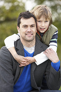 父亲和儿子抱抱 在外门秋日散步男性微笑中年宠物男生男人拥抱公园图片