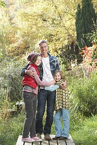 父亲和孩子们在秋天的 Wooden 走道上站在外面男人三个人享受儿子农村公园女孩中年男性父母图片