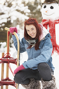 下至雪人与滑雪女孩微笑女性寒冷围巾风镜场景花园滑雪镜雪橇笑声图片
