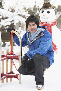 下到雪人与滑雪的少年男孩笑声男性下雪微笑季节寒冷围巾雪橇混血场景图片
