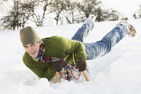 年青男子在雪地风景中的滑雪上骑车场地爬坡雪人男性寒冷微笑帽子围巾农村季节图片