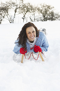 在雪地风景中的滑雪上骑车的年轻女子笑声帽子微笑手套场地下雪寒冷混血爬坡场景图片