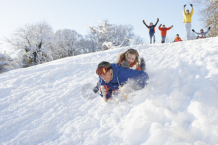 父亲和女儿有乐趣滑雪下山围巾季节儿子寒冷雪橇女孩笑声女性四个人微笑图片