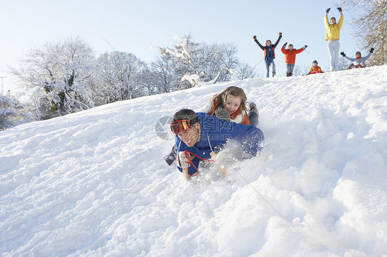 父亲和女儿有乐趣滑雪下山围巾季节儿子寒冷雪橇女孩笑声女性四个人微笑图片