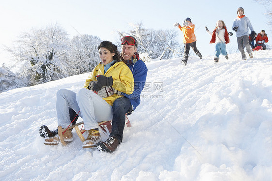 带着家庭守望的年轻夫妇滑雪下山图片