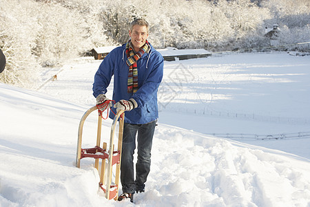 中年男子站在雪地景观控股悬崖水平场景下雪雪橇围巾微笑天气季节场地针织品图片