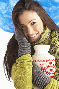 女青年穿着温暖的冬季温冬服装 装有热水瓶热水袋微笑下雪围巾寒冷笑声羊毛衣服拥抱天气图片