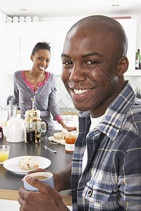 准备早餐的年轻夫妇在现代厨房烹饪面包咖啡男人女士成人男性果汁柜台建筑学橙汁图片