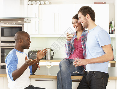 一群年轻朋友在现代厨房里享用一杯葡萄酒酒杯享受女士柜台三个人建筑学男人成人微笑团体图片