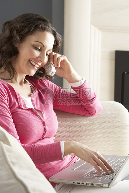 妇女使用膝上型电脑轻松地坐在Safa的家里谈P笔记本客厅长度娱乐沙发互联网微笑闲暇冲浪女性图片