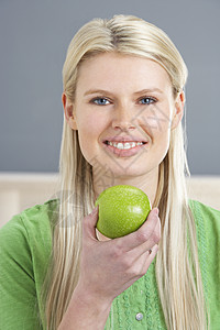 在家吃苹果时在沙发上放松妇女饮食女性金发健康水平享受长度成人水果客厅图片