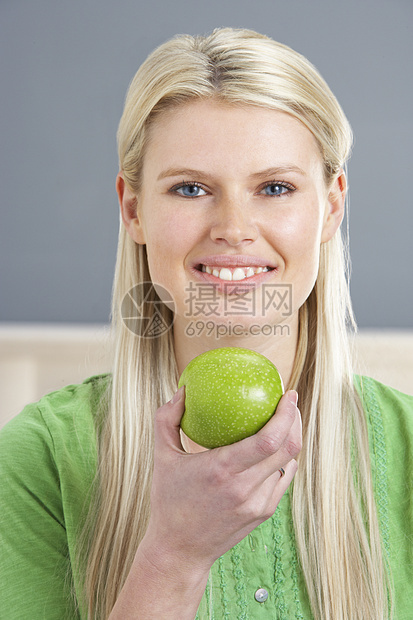在家吃苹果时在沙发上放松妇女饮食女性金发健康水平享受长度成人水果客厅图片
