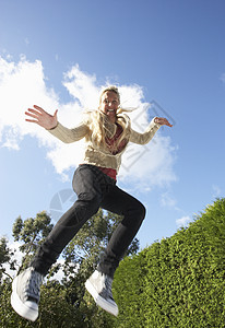 中空中抓获的少女在轨迹上跳跃蹦床低角度服装花园女郎金发休闲女性活力飞跃图片
