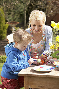母亲和儿子在外门桌外装饰复活节鸡蛋装潢享受孩子们花园两个人男人男生女性妈妈孩子图片