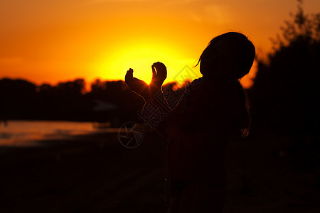 小女孩手握着日落的太阳蓝色生活愿望天空阳光女孩孩子点燃镜片耀斑图片