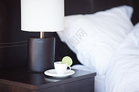 床铺和枕头 在床边桌子和灯台上喝茶木头床单窗户家具杯子亚麻寝具酒店毛巾停留图片