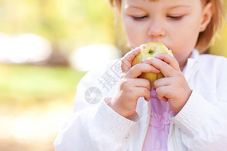 在秋林中吃苹果的美丽的小女孩儿幸福黄色叶子公园孩子食物季节女儿女孩橙子图片