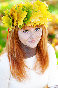 一位美丽的年轻红发女青年 在花圈的肖像女性地面微笑季节女孩公园学生乐趣喜悦金子图片