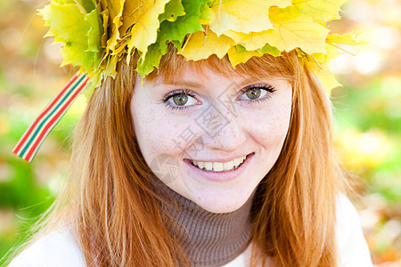 一位美丽的年轻红发女青年 在花圈的肖像季节乐趣地面喜悦成人森林叶子公园天气青少年图片