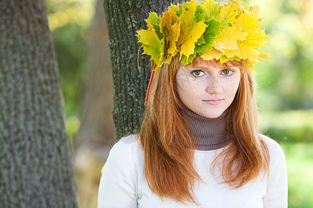 一位美丽的年轻红发女青年 在花圈的肖像金子女性微笑叶子享受森林喜悦季节青少年天气图片