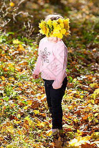美丽的小女孩 在秋前秋叶的青树叶花圈中微笑喜悦公园快乐黄色女性童年叶子幸福乐趣图片