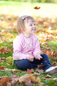 美丽的小女孩坐在秋天的树叶上童年喜悦黄色红色叶子女儿微笑幸福女孩快乐图片