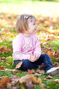 美丽的小女孩坐在秋天的树叶上乐趣童年微笑压痛女孩红色橙子季节幸福黄色图片