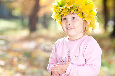 美丽的小女孩 在秋前秋叶的青树叶花圈中森林黄色橙子童年压痛喜悦乐趣季节公园微笑图片