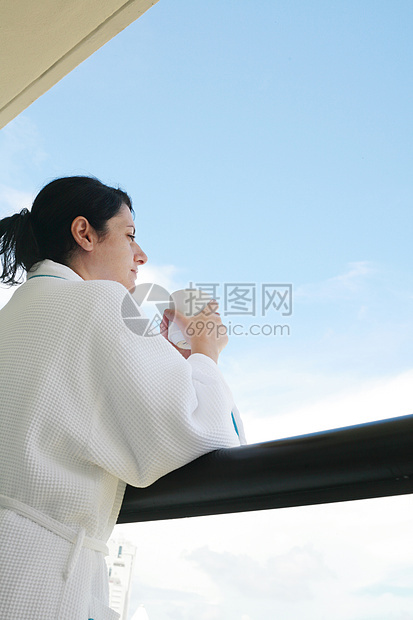 早上喝咖啡的女士通过阳台看图片