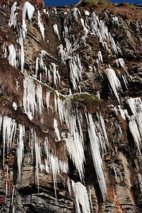 悬崖面上结冰的冰柱蓝色天空钟乳石岩石砂岩滴水环境石头冻结支撑图片