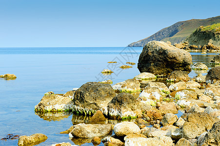 海岸的巨石阳光海洋海岸线波浪假期石头潮汐边缘反射地平线图片