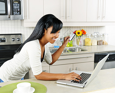 妇女在家里网上购物技术消费者购物信用商业卡片少数民族网络微笑借方图片