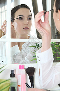 应用化妆的妇女睫毛膏刷子女士脸颊产品溶剂化妆品眼睛睫毛反射图片