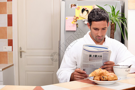 男人在吃早餐时看报纸图片