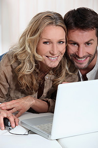 在笔记本电脑前的一对夫妇头发妻子男性女士女性白色金发丈夫棕色男人图片