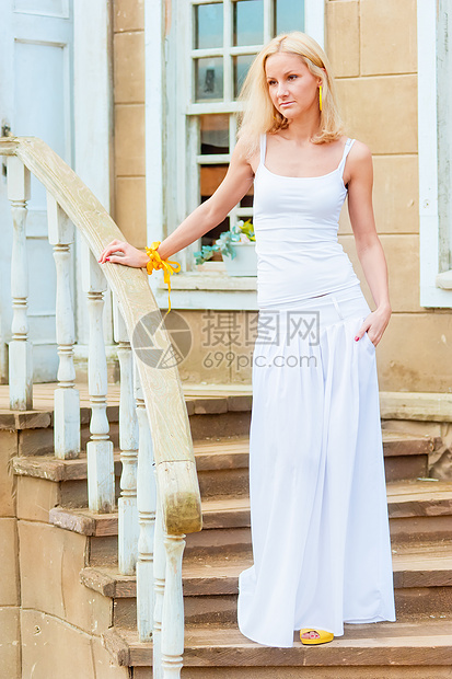 年幼的瘦女孩 在老宅前楼梯上微笑头发建筑脚步沉思蓝色阳光旅行女士快乐图片