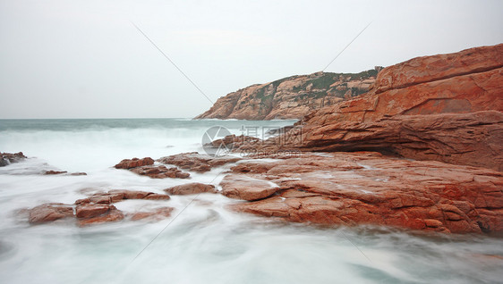 岩石海岸和模糊水域海洋石头太阳海浪波纹冲浪野生动物蓝色天空地平线图片