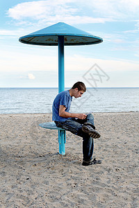 青少年在海滩上文学支撑座位场景海岸思维天空牛仔裤学习日落图片