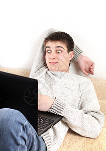 青少年用笔记本感到惊讶男人电脑说谎青年游戏毛衣头发男性男生互联网图片