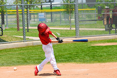 年轻棒球运动员挥棒球棒背景图片